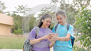 Happy Asian student girls walking and using smart phone in school