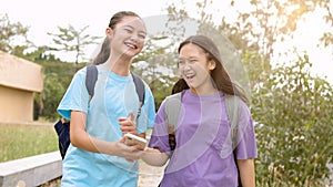 Happy Asian student girls walking and using smart phone in school