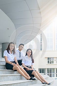 Happy asian students in uniform siting at university