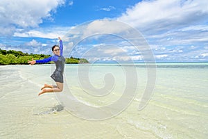 Happy asian teen girl jumping fun on the beach