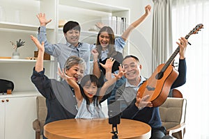 Happy Asian three generation family, grandparent, mother, father, daughter playing guitar, singing and having fun together,