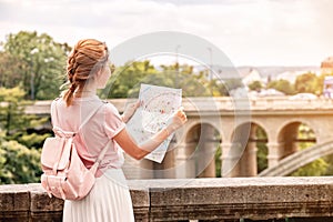 happy Asian traveler girl reads a map and searches for famous landmarks in the Luxembourg city district in Europe