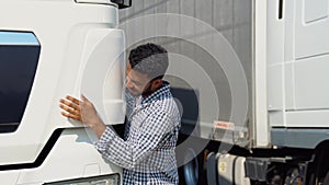 Happy asian truck driver loving his job. Indian trucker hugging his truck vehicle for transportation