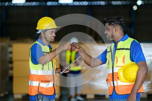 Happy Asian warehouse workers having fun and fist bumping during beginning start work in morning