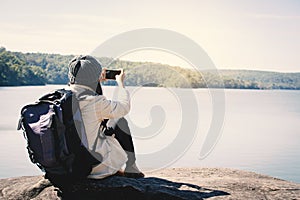 Happy Asian woman backpacker using smartphone shooting view of nature photo