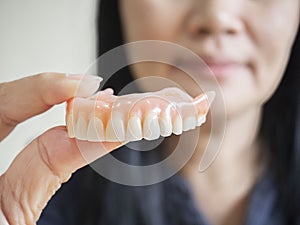 Happy asian woman be smile and holding dentures in hand