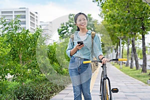 Happy Asian woman in casual clothes using a smartphone and a bicycle