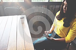 Happy Asian woman chatting on her mobile phone while relaxing in cafe during free time,