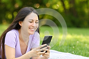 Happy asian woman checking mobile phone in a park