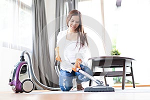 Happy Asian woman cleaning carpet with vacuum cleaner in living room. Housework, cleanig and chores concept