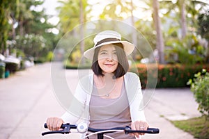 Happy asian woman cycling spreads legs on bicycle at park,Practice pedaling circles,Riding a bike