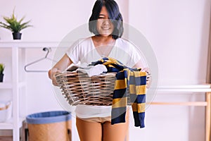 Happy asian woman doing laundry with basket at home