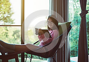 Happy asian woman drinking coffee and reading book in living room,Morning time,Relax and fresh