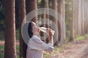 Happy Asian woman drinking fresh water in the forest.