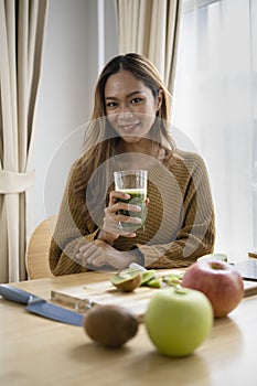 Happy asian woman drinking green detox vegetable smoothie. Healthy Lifestyle.