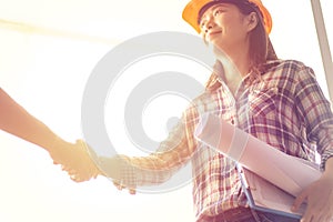 Happy Asian woman engineer as construction workers with blueprint