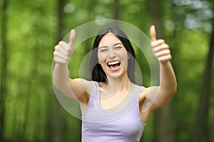 Happy asian woman gesturing both thumbs up in a park