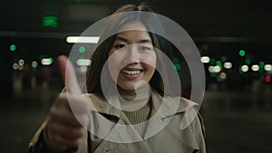 Happy Asian woman girl female shows thumb up finger gesture in parking joyful chinese korean businesswoman smiling