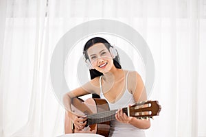 Happy asian woman hand playing guitar on bedroom in the morning,Relaxing time