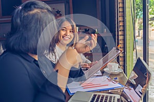 Happy Asian woman having discussion with partner in rustic cafeteria