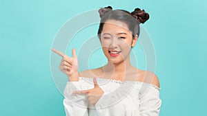 Happy asian woman having idea and winks at the camera over blue background