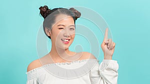 Happy asian woman having idea and winks at the camera over blue background