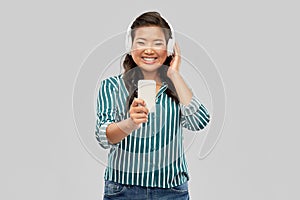 Happy asian woman in headphones listening to music