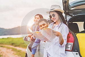 Happy Asian woman and her friends standing by car. Young girl having fun during road trip. People lifestyles and travel vacation