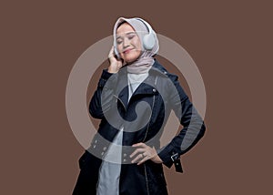 Happy asian woman in hijab enjoy listening music using wireless headphones