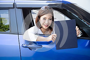 Happy Asian woman holding car insurance document book and sitting in car.