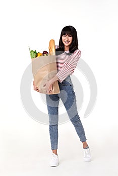 Happy Asian woman holding paper bag full of fresh vegetable groceries isolated on white background