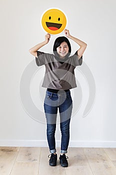 Happy Asian woman holding a smiley emoticon face
