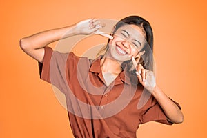 happy asian woman laughing while holding her cheeks.