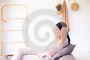 Happy asian woman looking on window while sitting on couch in living room with hands over head,Relax time