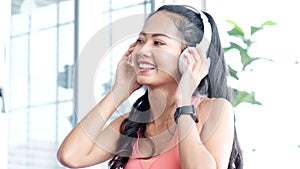 Happy asian woman modern wireless headphones listening to music after exercise at home