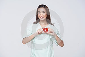 Happy asian woman patient showing heart isolated on white background. Insurance cardiovascular and cardiac concept