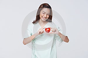 Happy asian woman patient showing heart isolated on white background. Insurance cardiovascular and cardiac concept