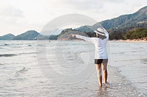Happy asian woman pointing something on the beach near sea while beautiful sunset time,Relaxing and enjoying concept
