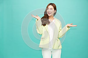 Happy Asian woman presenting or showing open hand palm with copy space for product isolated green background