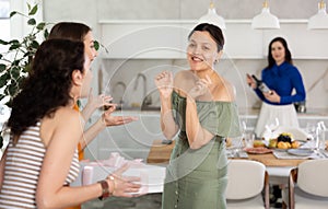 Happy Asian woman receiving gift from besties at birthday bash