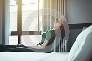 Happy Asian woman relaxing and stretch lazily in bedroom at home