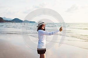 Happy asian woman selfie with mobilephone on the beach near sea while beautiful sunset time,Relaxing and enjoying concept