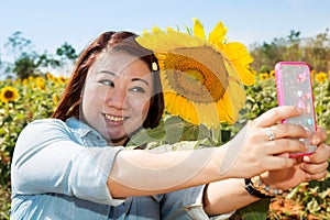 Happy asian woman selfy with sun flower in sunflower flower field.