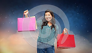 Happy asian woman with shopping bags on night sky