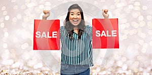 Happy asian woman with shopping bags over lights