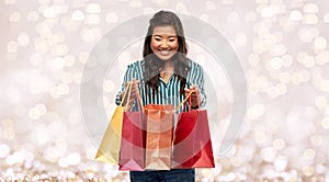 Happy asian woman with shopping bags over lights