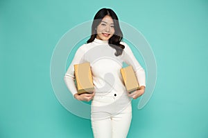 Happy Asian woman smiling and holding package parcel box isolated on light green background.