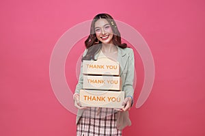 Happy Asian woman smiling and holding package parcel box isolated on pink background