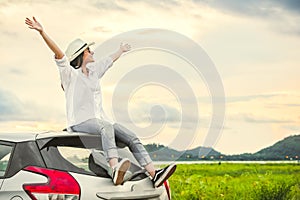 Šťastný ázijský žena rozšíriť ramená široko a čerstvý vzduch šťastie nálada v po západ slnka na auto strecha. 