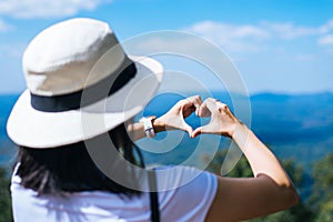 Happy asian woman standing and showing hands heart shape at nature,Free time,Positive thinking